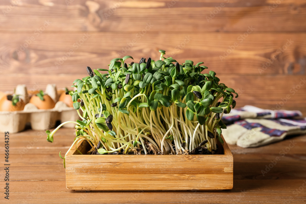 Box with green seedlings on wooden background