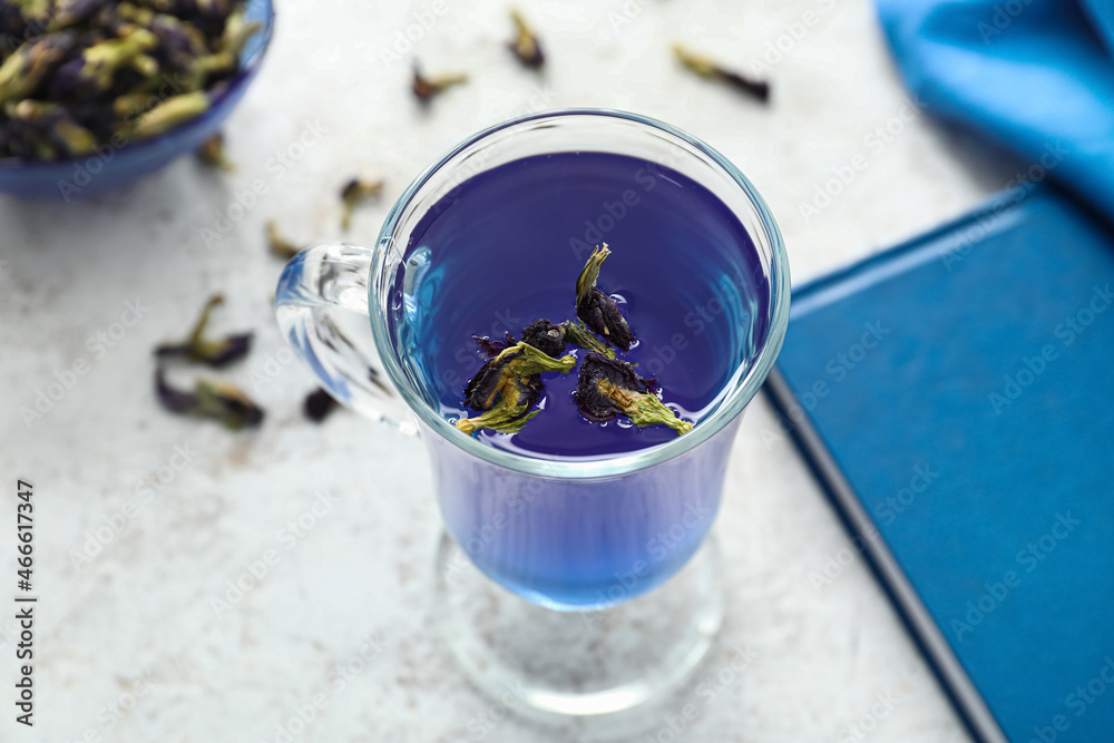 Glass of organic blue tea on light background