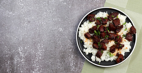 Wall Mural - Red braised pork with rice on a round plate on a dark background. Top view, flat lay