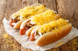 American chili hot dog with beef sausage, cheddar cheese and onions close-up on an old wooden background. horizontal