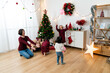 © PR Image Factory - wide angle of happy asian mother and kids playing with balloons in a festive living room decorated for Christmas at home