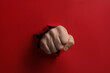 Man breaking through red paper with fist, closeup