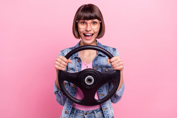 Sticker - Portrait of attractive cheerful amazed girl holding steering having fun isolated over pink pastel color background