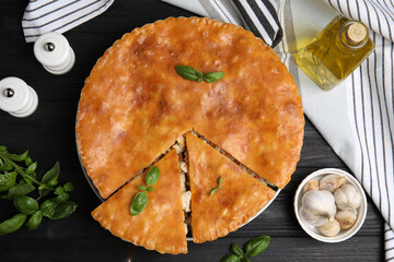 Delicious meat pie served on black wooden table, flat lay