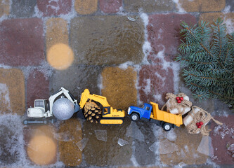 Wall Mural - toy excavators, dump truck with Christmas decorations on icy paving slabs. preparation for new year holiday . concept for Christmas business greetings in construction companies.