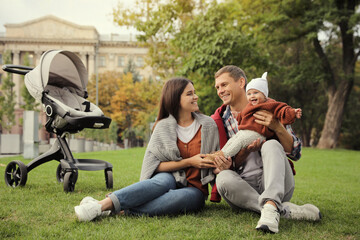 Canvas Print - Happy parents with their adorable baby on green grass in park