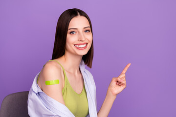 Wall Mural - Photo of optimistic brunette millennial lady indicate empty space did vaccination wear top shirt isolated on purple background