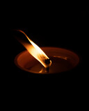 Fototapeta  - A flame of the candle. Candle burning brightly on dark background. Selective focus. 