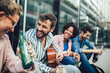 © Mediteraneo - Group of young friends hangout in city.They are sitting,singing and playing guitar.