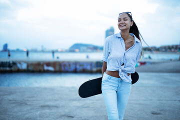 Fashion woman with skateboard. Young happy girl enjoy near the ocean..