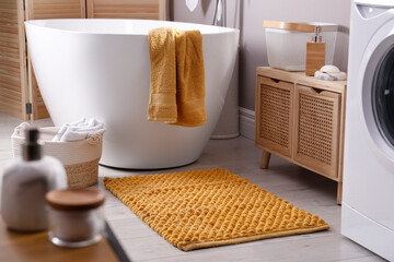 Wall Mural - Soft orange mat on floor near tub in bathroom. Interior design