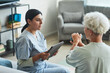 © Seventyfour - Portrait of female nurse using digital tablet while talking to senior woman in retirement home, copy space