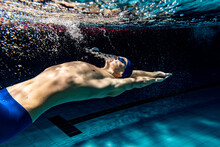 Underwater Shooting. One Male Swimmer Training At Pool, Indoors. Underwater View Of Swimming Movements Details.