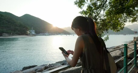 Canvas Print - Woman use mobile phone with sea view under sunlight flare