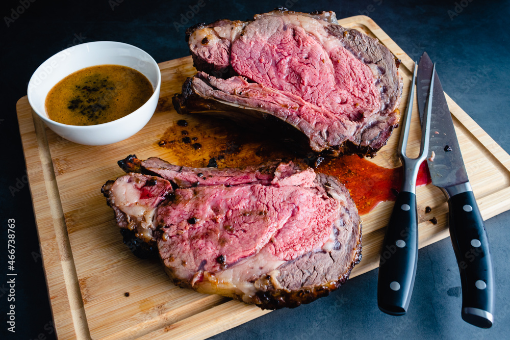 Slices of Medium Rare Bone-in Prime Rib with Au Jus: Carved standing ...