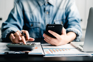 Canvas Print - Close up of young women or female entrepreneur using smartphone and calculator working business report analytic at home, accounting document, marketing and financial business concept.