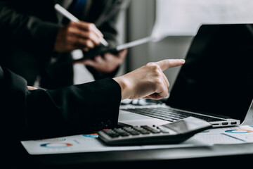 Close up of businesspeople discussing and using a laptop with analysis chart graph business report at the workplace, investor trading stock market, project planning, financial and investment concept.