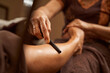 Experienced masseuse using wooden tool during traditional Thai foot massage