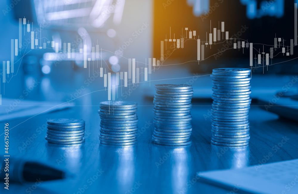 Stack of money coin and laptop computer in the background with trading graph, Business and Financial concept. 