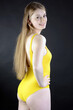 Cheerful girl posing in yellow one piece swimsuit in studio	
