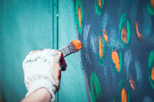 A Hand Holding A Paint Brush And Painting A Wall