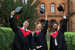 © Тарас Нагирняк - Multinational graduates male and female celebrating graduation in university campus, removing their graduation hats and smiling to the camera
