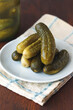 Bowl with pickled gherkins, cucumbers on wooden background.