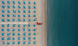 © AmazingAerialAgency - Aerial view of a well sorted lido with blue parasols and sunbeds at sunrise along the coastline in Calabria, Italy.