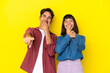 © luismolinero - Young mixed race couple isolated on yellow background pointing with finger at someone and laughing a lot