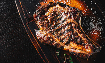 Sticker - Grilled Ribeye Steak on bones on wooden board, prime cowboy steak on dark background