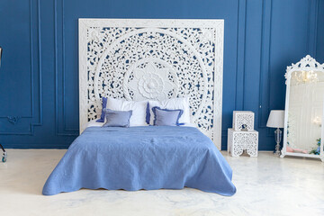 Beautiful luxury classic clean interior bedroom in white and deep blue color with king-size bed and chic carved furniture. Bright modern stylish interior bedroom and living room in minimalist style.