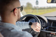 © Julija - business man in car on road looking on smartwatch.