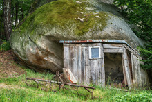 An Old Rustic Garden Shed With A Huge Mossy Stone As A Roof. A Photo In High Dynamic Range Technique (HDR)
