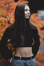 Teenage Girl Stands In Front Of Fall Colored Leaves In Autumn