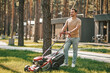 © zinkevych - Young man standing with lawn mower