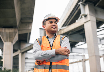 Asian engineer handsome man or architect looking construction with white safety helmet in construction site. Standing at highway concrete road site.