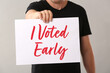 © Pixel-Shot - Man holding poster with text I VOTED EARLY on grey background