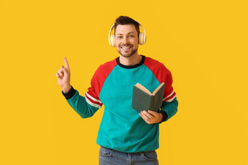 Sticker - Man with headphones and book pointing at something on color background