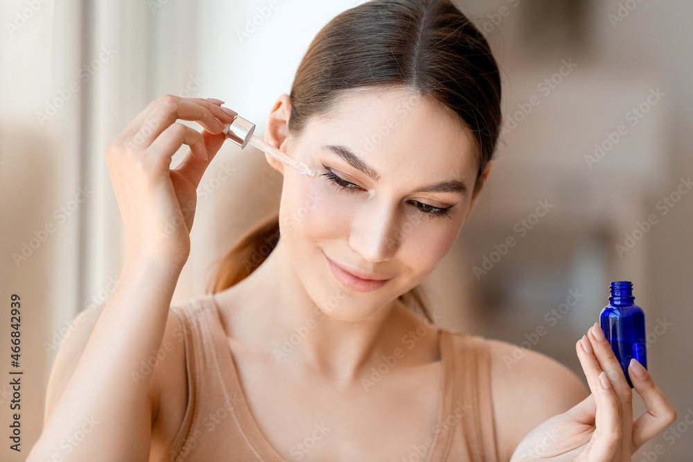 Beautiful woman applying natural essential oil on face