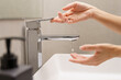 Saving water concept, Close up of beautiful female's hands turning on a faucet with water drop coming out. Crisis, Ecology, World water day, Running out, Stop spreading Covid 19, Handwashing, Clean.