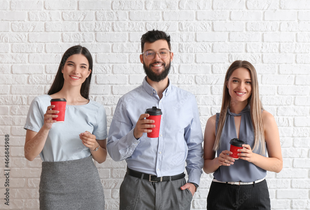 Business people with coffee on white brick background