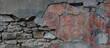 Old stone wall covered with cement. Half of cement on this wall is crumbled. There are cinderblocks under the cement. Panorama.	
