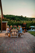© bernardbodo - Cheerful three generations family having dinner together around a table in the backyard