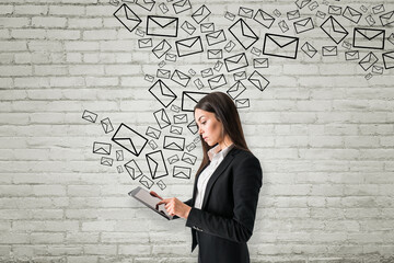 Aufkleber - Portrait of attractive young european businesswoman using tablet with creative drawn email icons on white brick wall background. Business, technology, communication and e-mail marketing concept.