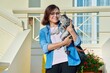 Middle-aged woman with her pet cat in her arms at home outdoors.