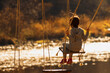 © zwiebackesser - Young girl having fun on swing outdoor against on the background of the river and forest. Horizontal image.