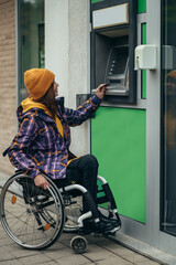 Woman in wheelchair using credit card and atm machine