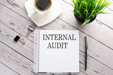 Poster - Cofee cup, notepad,pen on the wooden background. Business concept. Text INTERNAL AUDIT