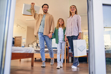 Wall Mural - Young happy family with cute daughter leaving joyful out of the store with purchases of new pillows. Shopping for mattresses, beds and other bedding.