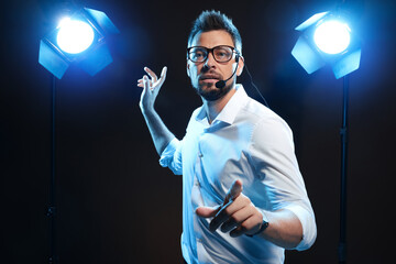 Motivational speaker with headset performing on stage. Space for text